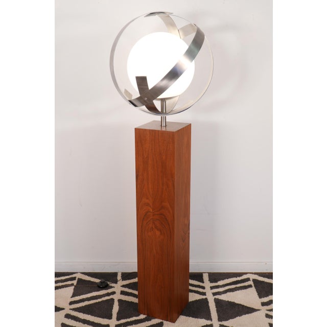 This Saturn floor lamp made by the Laurel Lamp Co. features banded aluminum curved around an opaque white glass globe and...