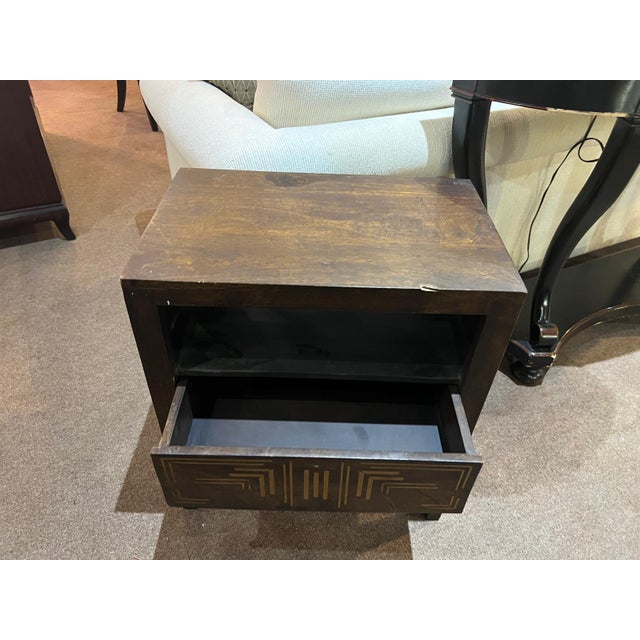 A distinctive wood side table with a decorative inlay drawer, featuring a bold open-frame design and striking geometric...