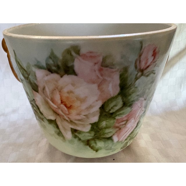 An antique franc porcelain footed cachepot probably from Limoges. The piece features hand painted pink and peach roses on...