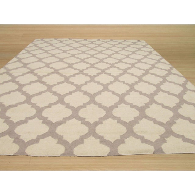 A handwoven wool flatweave, made in India and measuring 5'6"' x 8'. Geometric drawing across the field. Flatweaves carry...