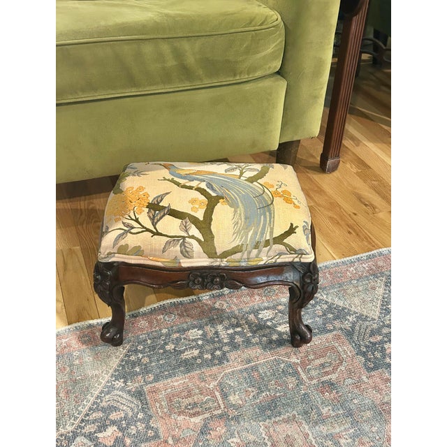 This petite Louis XV style footstool is nicely carved of mahogany with florals and is reupholstered in a 100% linen...
