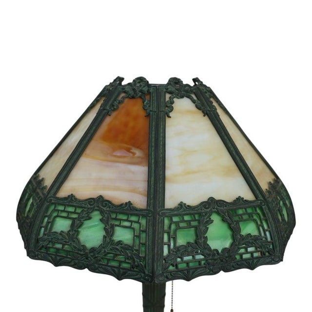 This antique Arts & Crafts table lamp, in the manner of Bradley & Hubbard, features an eight-panel slag glass shade. The...
