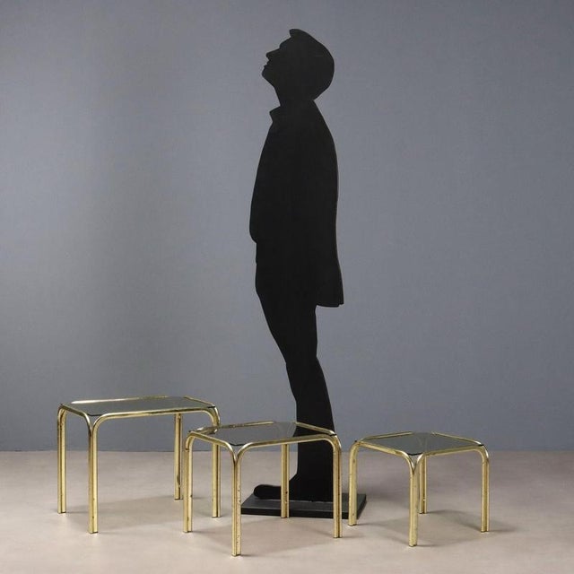 Set of three nested tables with brass frames and smoked glass tops of varying sizes. This piece is attributed to the...