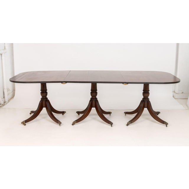 Regency Style Mahogany Metamorphic Extending Pedestal Dining Table, the canted corner top above triple pedestal base, with...