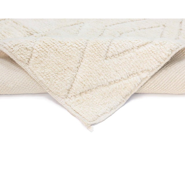 Elegant Hand-knotted wool rug featuring a Natural Ivory tone accented with a geometric diamond design in a subtle relief...