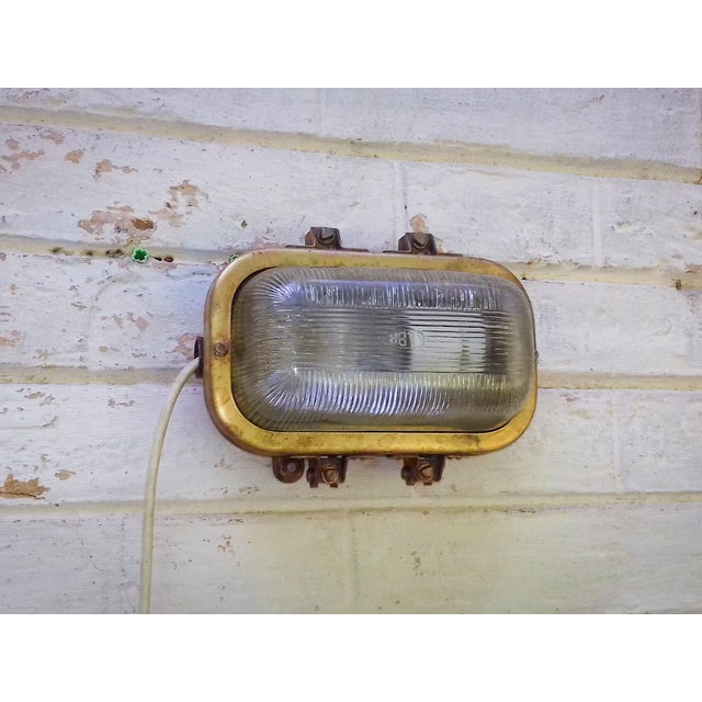 Vintage industrial bulkhead wall light made in Romania, featuring a substantial brass-toned metal body and thick ribbed...