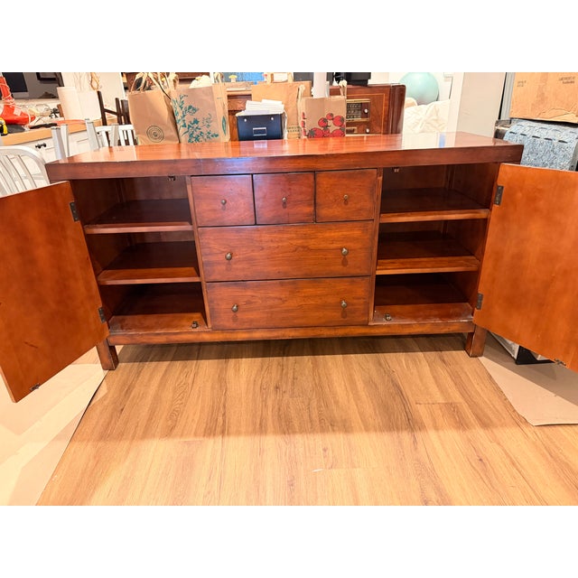 We are selling our Mitchell Gold + Bob Williams sideboard / credenza. It's a warm walnut-toned wood finish with red...