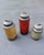 A charming set of three handcrafted stoneware lidded jars featuring earthy ochre, oxblood red, and soft sage green glazes...