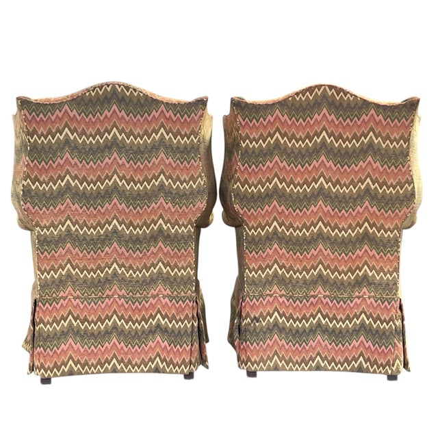 Each chair features a traditional wingback silhouette with tall, shaped backs, gently flared wings, and rolled arms that...