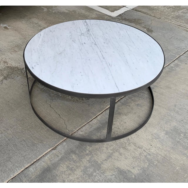 A Carrara marble-top coffee table with an Iron finished round base. The top is new and the base is vintage. We had to...