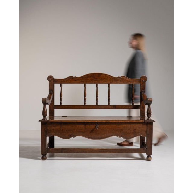 This piece presents as a bench with lift seat, distinguished by dark aged oak, carved crest, storage compartment....