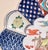 A vintage Japanese hand-painted porcelain plate in an Imari-inspired style, featuring a richly detailed central scene of a...