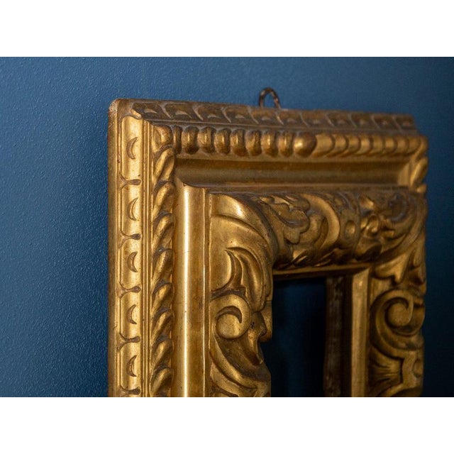 Refined 18th-century Italian wooden frame finely carved and gilded with gold leaf, featuring rich decoration with scrolls,...
