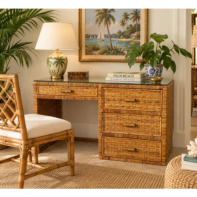 This 1970s Vintage Boho Coastal Rattan Writing Desk features intricate craftsmanship in a warm, natural honey finish....