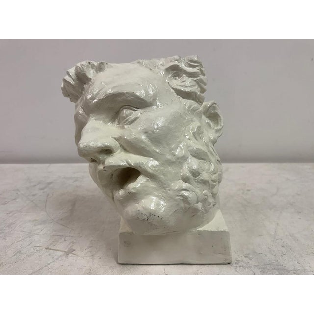 A striking plaster model of a classical male head, rendered with expressive movement and dramatic character. The face is...