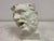 A striking plaster model of a classical male head, rendered with expressive movement and dramatic character. The face is...