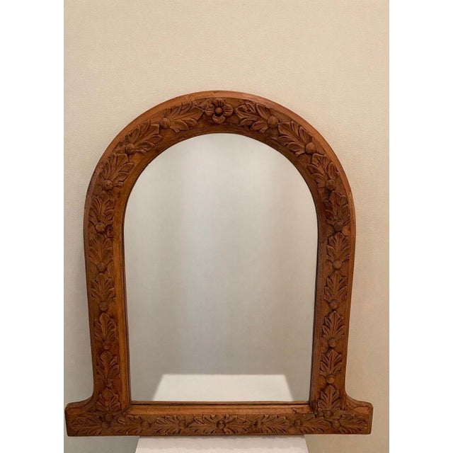 Late 19th century French provincial mirror with hand-carved foliate and berry relief framing a softly arched silhouette....