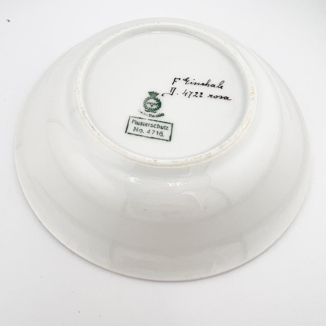 A refined antique German porcelain display plate featuring a delicate pink-to-white cameo-style ground and a raised...