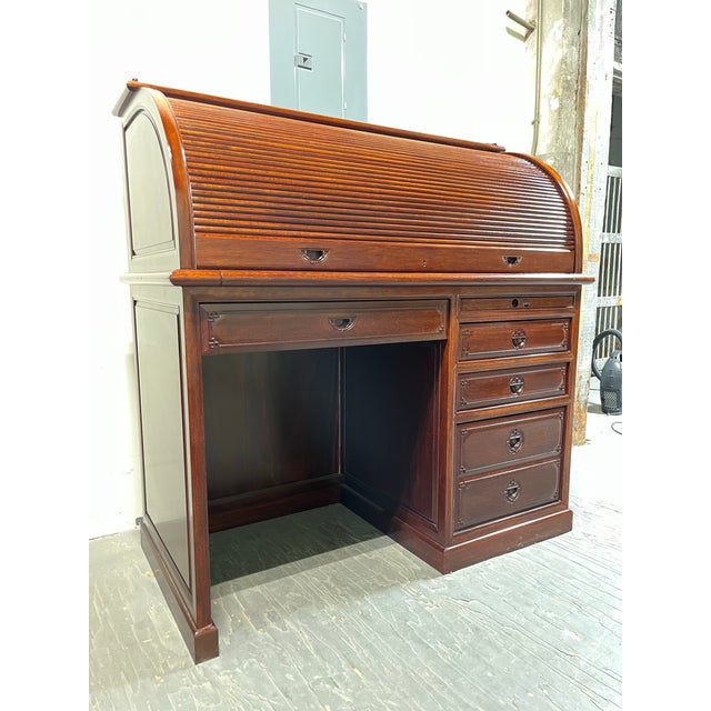A handsome vintage roll-top desk crafted in the Asian Modern manner, featuring a beautifully figured mahogany-toned finish...