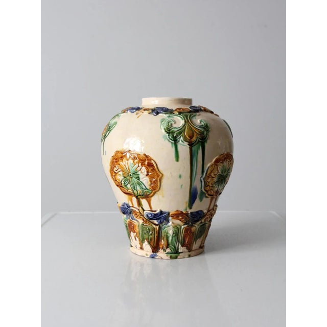 This art pottery vase reflects the Tang sancai style, featuring molded floral ornament beneath flowing polychrome glazes...