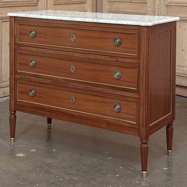 Antique French Louis XVI Mahogany Commode with Carrara Marble combines the stately, tailored elegance with a luxurious...