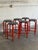 This vibrant set of six bar stools features bold red tubular metal frames paired with dark round seats. The stackable...