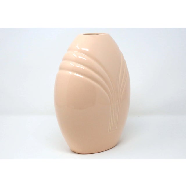 A vintage, ceramic vase with linear details and a peach-colored glaze. Good condition.