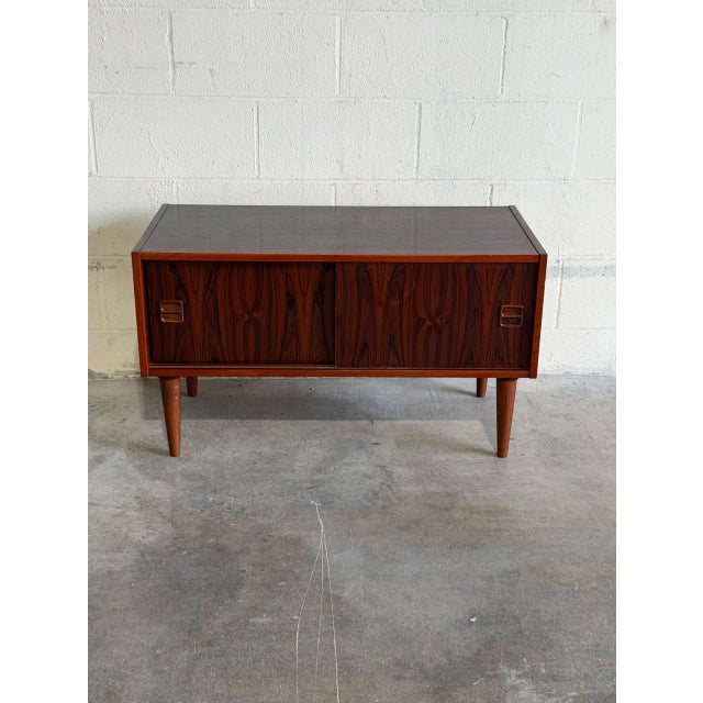 This compact storage piece features a clean rectilinear form and sleek sliding doors that reveal an undivided interior...