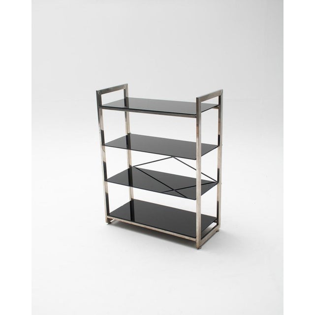 Set of two chrome-plated metal shelving units with dark black tempered glass shelves, inspired by the industrial and...