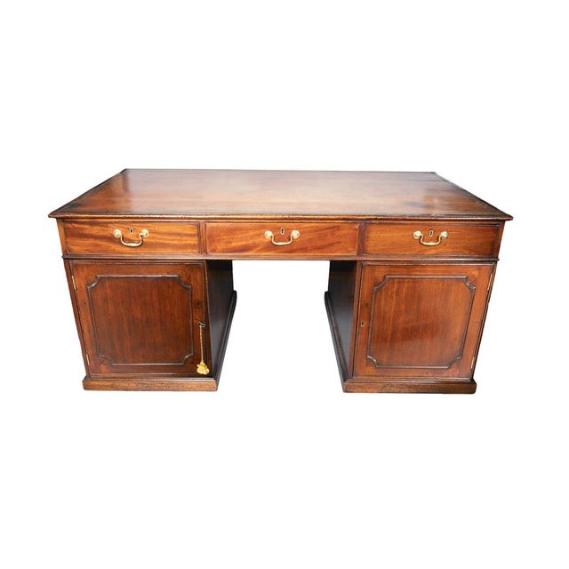 With a rectangular tooled brown leather top with cross-banded edge over a frieze containing three drawers with brass bail...