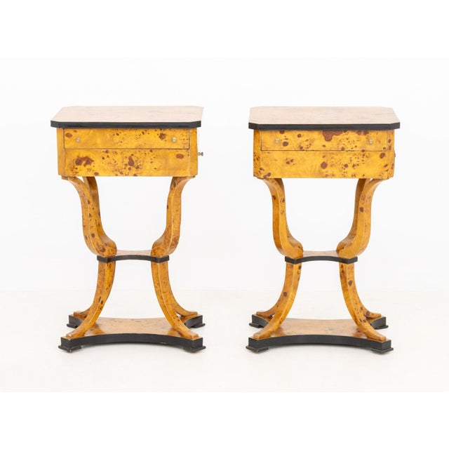 Pair of Biedermeier Partial Ebonized Burlwood Sewing Tables, each top with canted corners and lifting to divided interior...