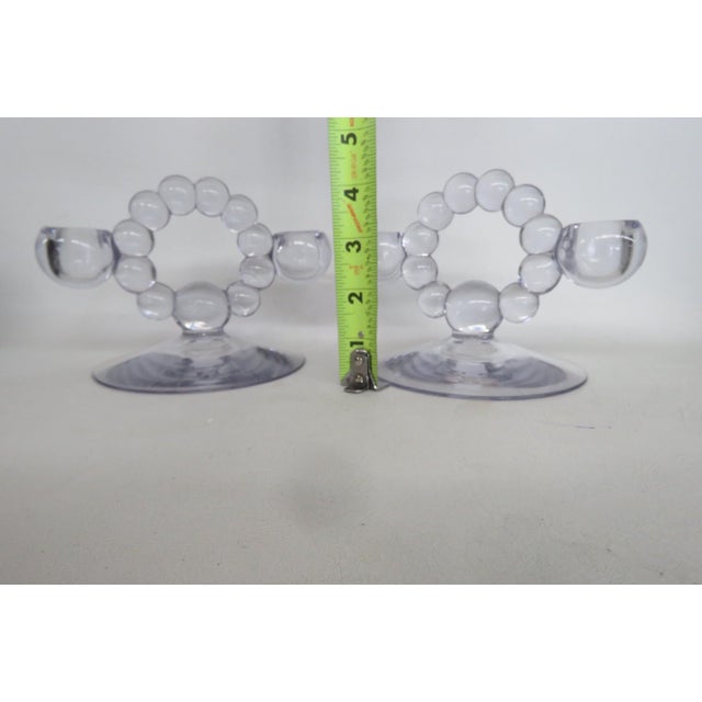 This charming Pair of Candle Holders is made of glass. These lovely candle holders feature a double taper design to fit...