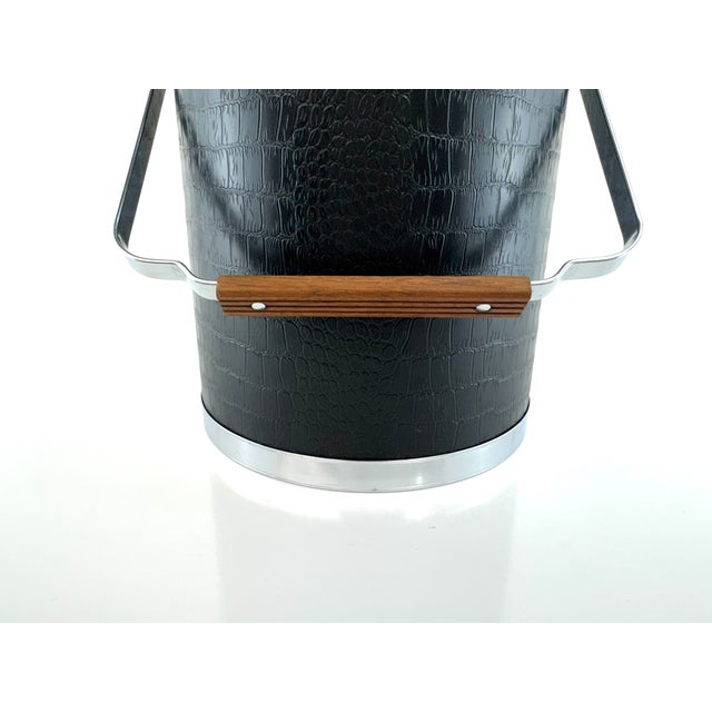 A 1960s ice bucket attributed to Kromex, combining black faux-alligator embossed vinyl with polished chrome and warm wood...