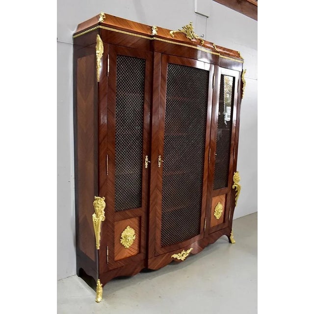 Louis XV style bookcase, with a central protruding part. It opens by three doors, with brass grills. These doors are...