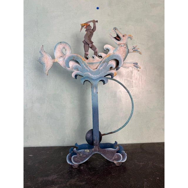 A highly decorative and whimsical cast iron figural andiron, featuring a dramatic narrative scene of a medieval knight...