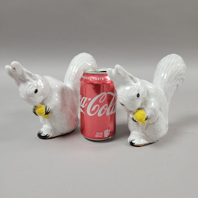 A charming pair of Italian white glazed squirrels nibbling on a nut. Hand molded, glazed and painted, each squirrel unique.