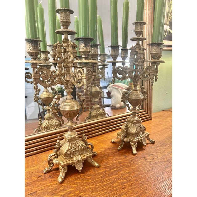 A dramatic pair of Continental Rococo Revival candelabra featuring elaborate scrolling arms, griffin-form handles, and...