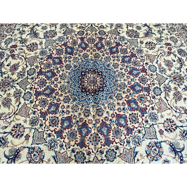 This Isfahan rug features a finely drawn central medallion surrounded by symmetrical floral and vine motifs executed with...