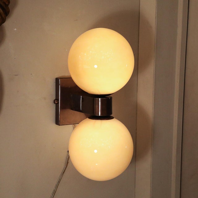 A striking pair of Modernist hand-blown Murano golden moon hue glass double sphere sconces with bronze accents, Italy,...