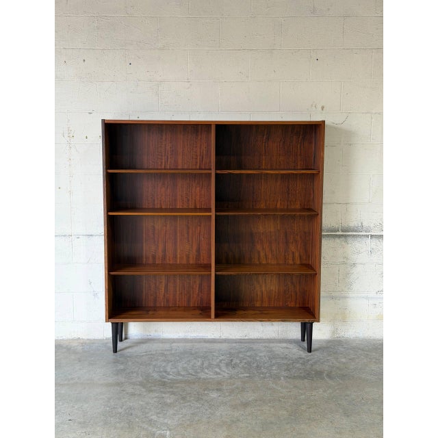 This spacious open storage unit features clean lines and adjustable shelving supported by tapered legs. The rich grain...