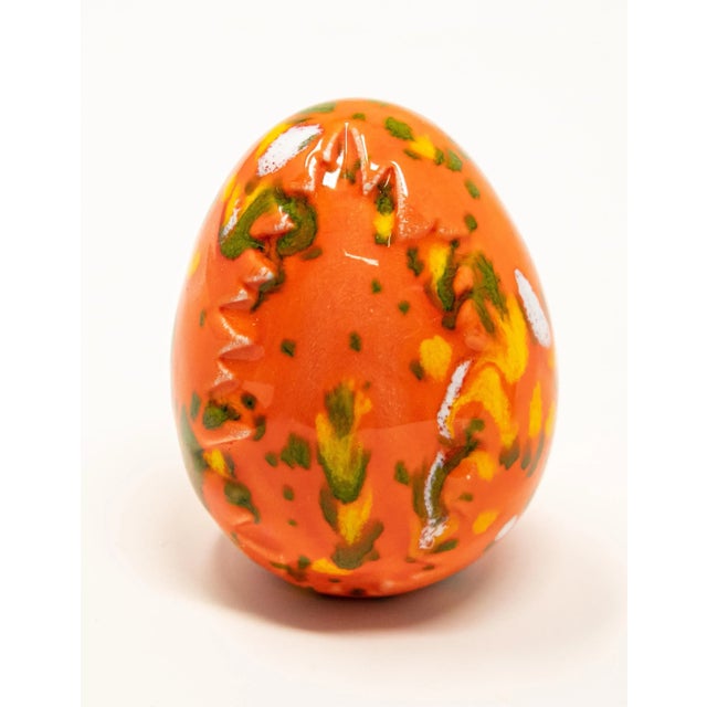Offering this pair of ceramic glazed eggs. One is bright orange with green and yellow, and has a tree stamped in it. The...