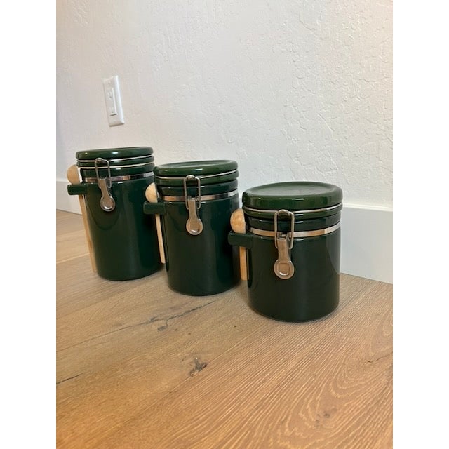 Vintage ceramic canisters featuring stainless steel metal fittings and accompanying wooden spoons. Set of 3. Diameter 5"....