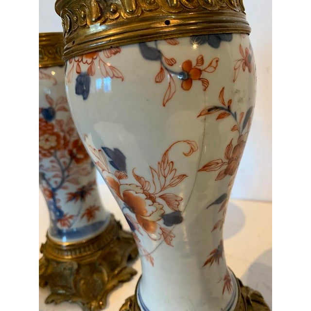 A lovely pair of imari porcelain lamps depicted with birds, foliage, and flowers beautifully mounted in chased and gilded...