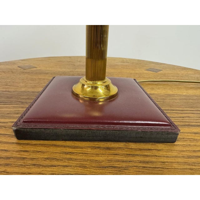 A refined table lamp combining brass and leather, executed in a restrained, tailored style. The lamp is composed of a...