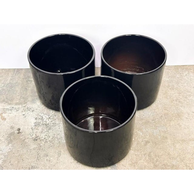 A set three of Gainey black-glazed ceramic planters. Drainage holes were added to ensure plant growth. The planters are in...