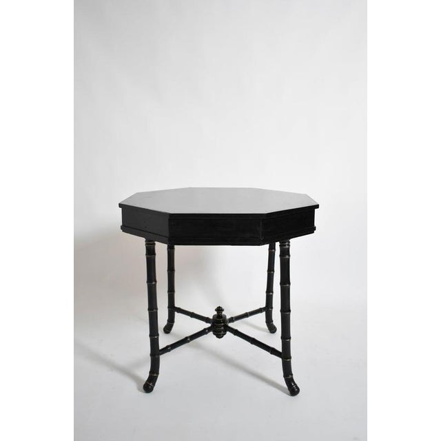 Faux bamboo octogonal table, 1910s. Ebonised wood octagonal table with four faux bamboo wooden legs joined by a spacer in...