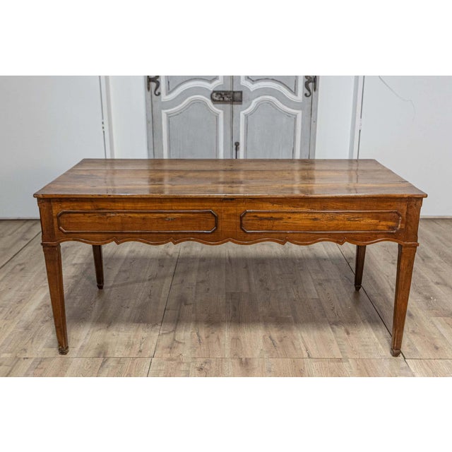 A French walnut desk from the 19th century with carved apron and lateral drawer. This elegant French walnut desk from the...