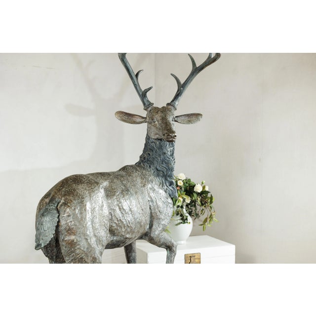 This impressive vintage bronze sculpture depicts a stag poised mid-stride upon a rocky base, a commanding presence that...