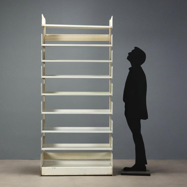 This 1970s-style bookcase/shelf is crafted from white lacquered metal and features a functional and versatile design. The...