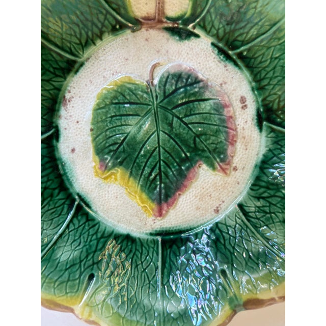 Decorative Majolica decorative bowl with leaf in center. Green colorway with yellow, brown and off-white accents.